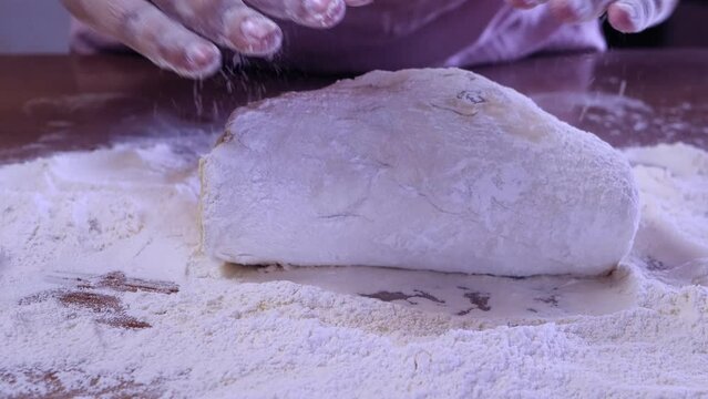 The hands of a Jewish woman form dough pieces for challah on the table. Medium plan