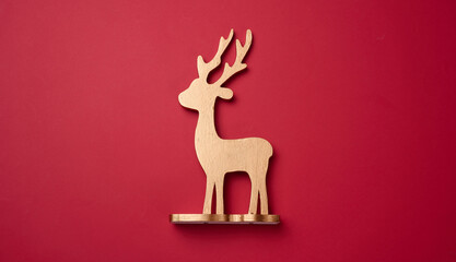 Golden wooden deer toy on a red background, top view. Christmas decor