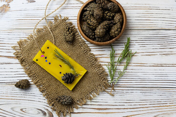 Aromatic plate of wax with the addition of rosemary on a canvas napkin. Cones in a wooden bowl in...