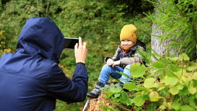 Young father making photo with little happy son boy traveling in the mountains forest together enjoying nature autumn beauty. Family lifestyle activity. Healthy tourism.