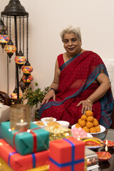 grandmother wearing saree an ethnic wear celebrating diwali Hindu festival with sweets gifts, candles