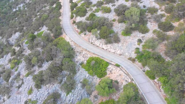Kurviger Bergweg in Italien auf der Insel Sardinien mit mediterraner Landschaft und Bergen im Hintergrund