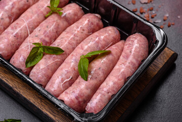 Raw sausages with ingredients on a cutting board on a dark concrete background with copy space