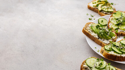 Vegetarian green sandwiches with avocado and cucumber with microgreens on a light background
