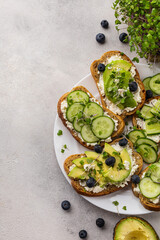 Vegetarian green sandwiches with avocado and cucumber with microgreens on a light background