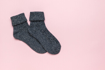 Dark knitted socks on a light pink background. Minimal footwear concept.