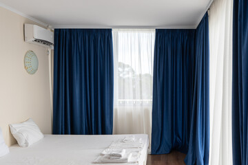 The interior of a hotel in a southern resort by the sea with white and blue curtains, a bed