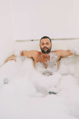 Hombre latino de mediana edad disfrutando de un baño con espuma y burbujas