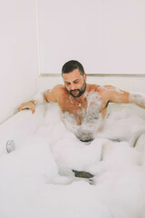 Hombre latino de mediana edad disfrutando de un baño con espuma y burbujas