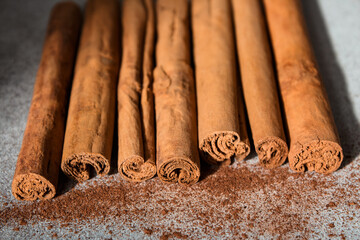 Ground Ceylon cinnamon sprinkled in front of real cinnamon sticks on a light background