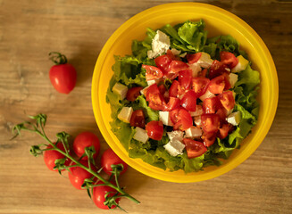sprig of cherry tomatoes, homemade light salad of lettuce, tomatoes, feta cheese and canned salmon. home cooking.