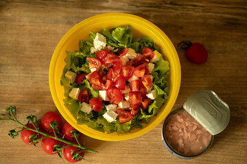 sprig of cherry tomatoes, homemade light salad of lettuce, tomatoes, feta cheese and canned salmon. home cooking.