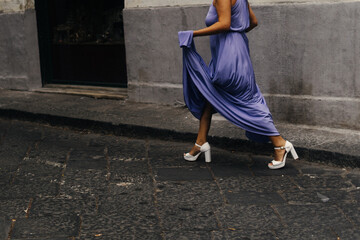 woman wearing an elegant dress crosses a street in Italy