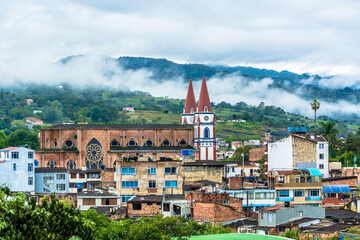 Fototapeta na wymiar Landscape view of Moniquira, Boyaca, Colombia with a big church, buildings. Green mountains with fog and clouds in the background