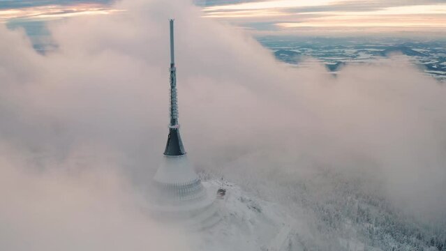 Spire of Jested tower seen through dense fog on winter day. Unique piece of architecture built on high mountain top in Czech Republic aerial view