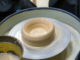 A close-up of a clay mold spinning on a potter's wheel. Handmade, craft, clay modeling, selective focus
