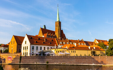 Holy Cross collegiate gothic cathedral rising over Ostrow Tumski Island and Odra river in historic old town quarter of Wroclaw in Poland - obrazy, fototapety, plakaty