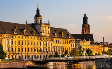 Obraz premium Historic old town quarter with Wroclaw University and Grodzka street embankment at sunset over Warta River in Wroclaw in Poland