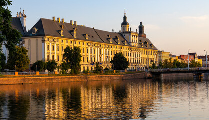 Historic old town quarter with Wroclaw University and Grodzka street embankment at sunset over Warta River in Wroclaw in Poland - obrazy, fototapety, plakaty