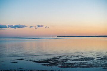 Obraz premium A beautiful calm sea at dusk. The light is delicate and golden. The water at low tide has gently ripples. The pier at Deal can be seen on the horizon.