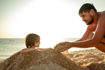 Dad will bury his son in the sand. The family spends holidays at sea. The concept of a happy family
