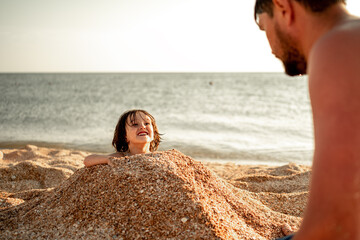 Dad will bury his son in the sand. The family spends holidays at sea. The concept of a happy family