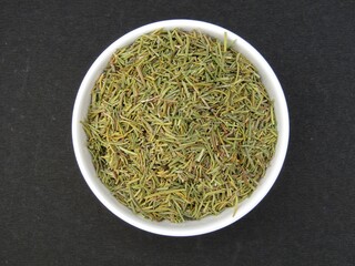 Dried rosemary leaves in a bowl top view 