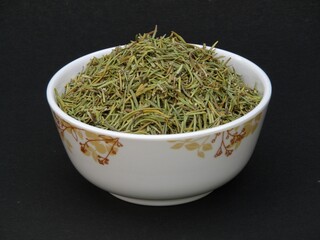 Dried rosemary leaves in a bowl on black background 