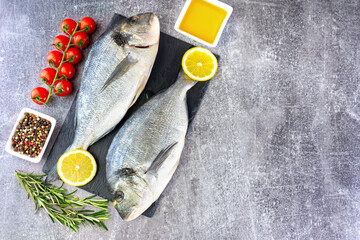 Dorado fish on gray concrete background with copy space. Sea food with ingredients for cooking. Delicacy spices and vegetables. Banner, header, background for menu and restaurant recipe