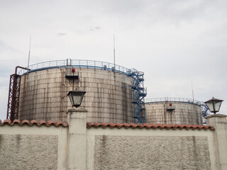 Large fuel tanks. Tanks and ladders of the tank farm. The gloomy atmosphere of an industrial area.