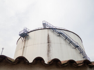 Large fuel tanks. Tanks and ladders of the tank farm. The gloomy atmosphere of an industrial area. Oil storage.