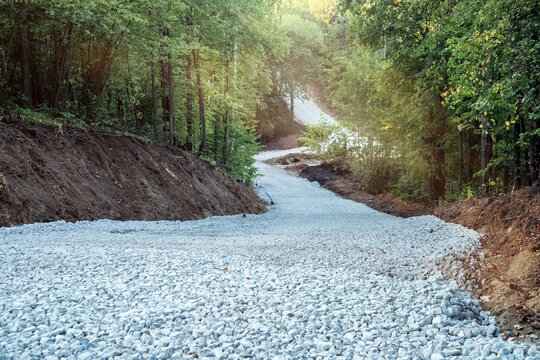 Construction of a new winding road through the forest. Prepared crushed stone substrate for asphalt paving.