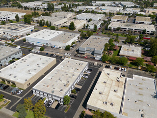Nondescript warehouse and industrial office buildings are shown during the afternoon from an aerial view.