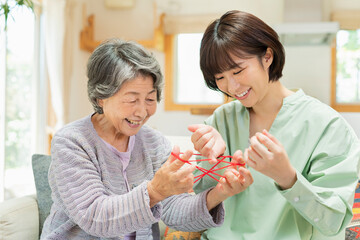 孫とあやとりをするシニア女性