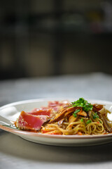 Gourmet pasta with seared tuna, mushrooms, and fresh chives served in a contemporary restaurant setting.