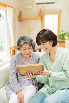 孫と写真を見るシニア女性