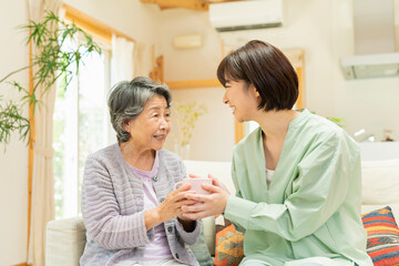 Obraz premium 自宅 一緒にお茶を飲む祖母と孫