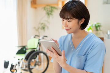 タブレットで日誌を書く女性医療従事者