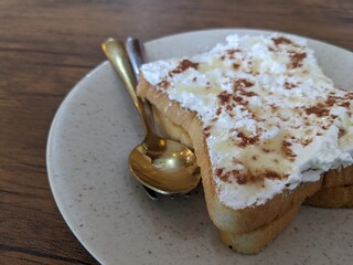 Close up photo of white mochaccino cream toast with white plate and wooden table. The photo is suitable to use for food poster, pamphlet and menu background.