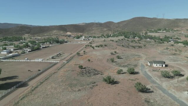 The arid landscape of rural Agua Dulce, California (located in the Sierra Pelona Valley, north of Los Angeles) is shown in an aerial view during the day.