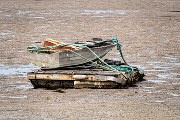 small boat strapped on platform on ocean ground with low water