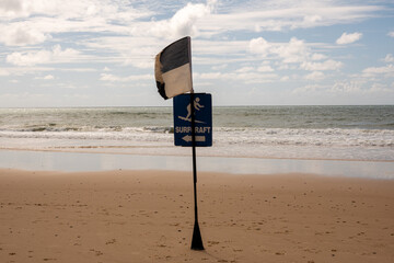 sign that says surf craft with ocean in background and blue and white flag