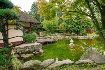 A teahouse and pond and lantern and reflections in the Japanese garden of the Botanical Garden "Planten un Blomen".in Hamburg