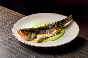 Fried sea bass with creamy pesto sauce on plate