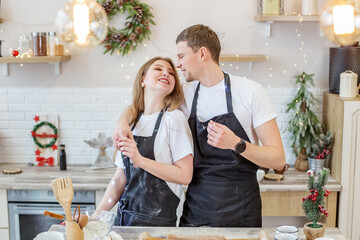 Young happy couple enjoying and preparing christmas cookies together in their kitchen.