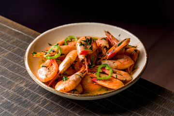boiled shrimp on bowl with sauce and chili peppers