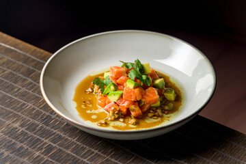 salmon Tartar on a plate with avocado on wooden table