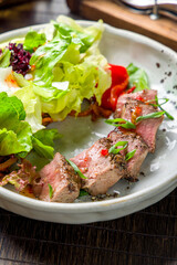 Salad with roast beef and greens with green onion and sauce vertical macro close up