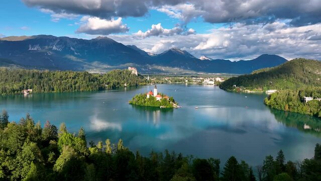 4K aerial footage of flying around Pilgrimage Church of the Assumption of Maria above Lake Bled on a beautiful autumn day with clouds. Lake Bled, Slovenia.
