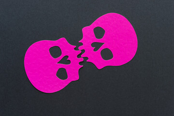 double hot pink skull heads joined at the teeth on black paper